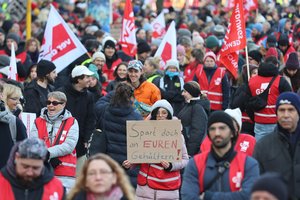 Demonstrierende in Berlin gegen Haushaltskürzungen tragen Gewerkschaftsfahnen und -westen sowie ein Pappschild, auf dem steht: "Spart doch an euren Gehältern!"; Foto: (c) DGB/Christian von Polentz